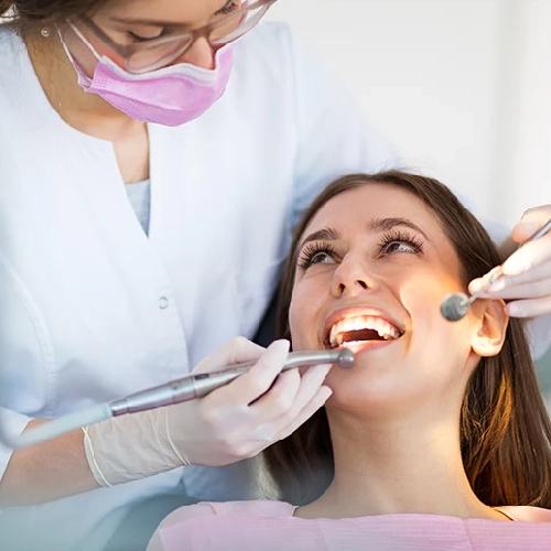 Dentist examining a smiling patient's teeth with a dental mirror