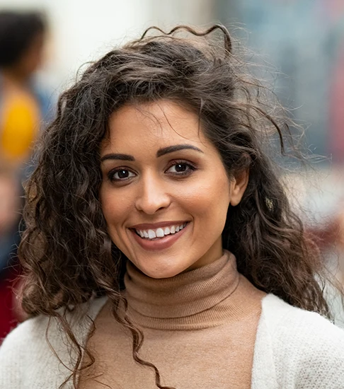 Smiling woman with curly hair showing a confident, natural-looking smile