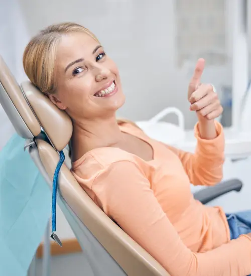 Smiling patient giving a thumbs up from the dental chair