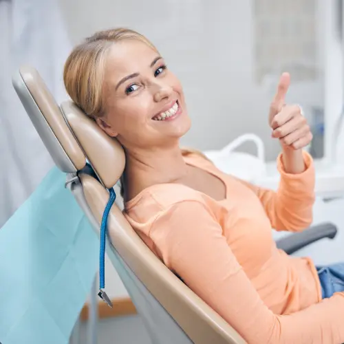 Smiling woman in a dental chair giving a thumbs up