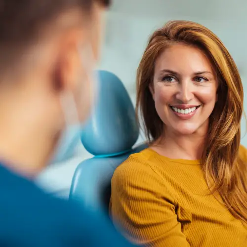 Smiling woman in a dental chair talking with her dentist