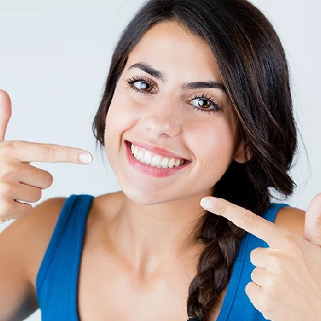 Woman pointing to her bright, even smile
