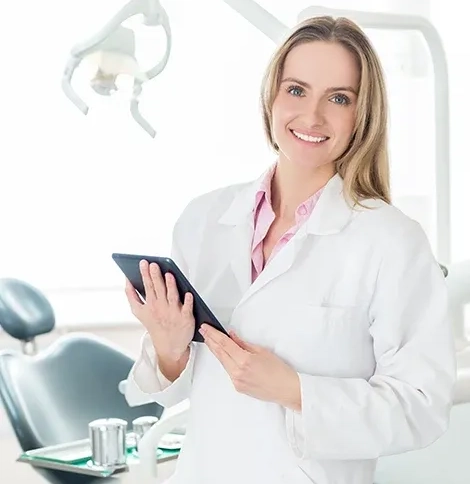 Smiling dental professional holding a tablet in a treatment room